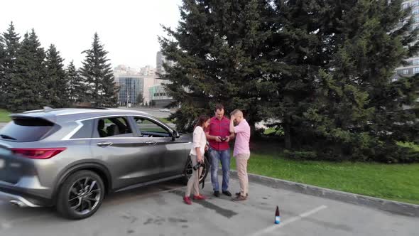 a Group of Friends Stands By the Car in the Background of a City