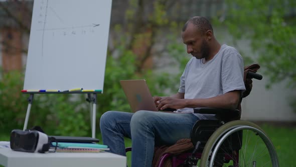 Focused Concentrated Disabled Man in Wheelchair Typing on Laptop Keyboard in Slow Motion