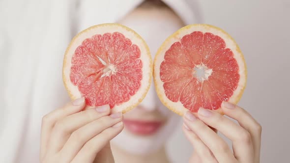 Smiling Young Cute Girl with a White Towel on Her Head and White Nutritious Mask on Her Face Hiding