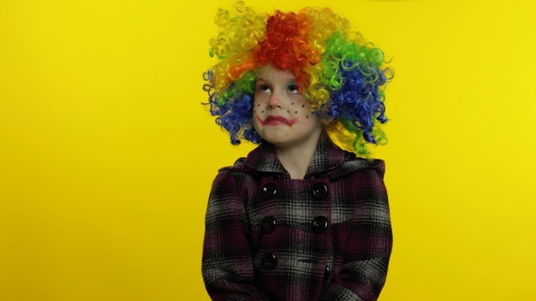 Little Child Girl Clown in Colorful Wig Making Silly Faces, Looks with Eyes in Different Directions