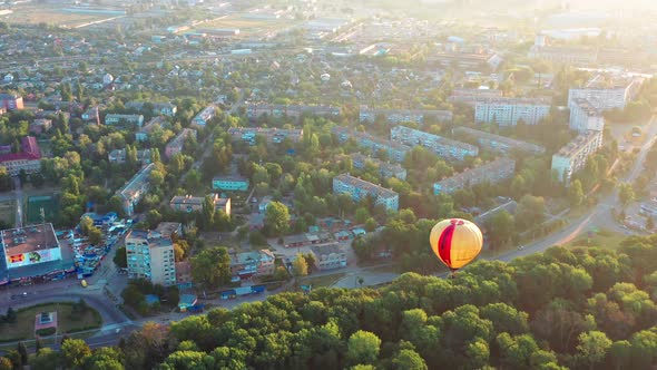 Beautiful sunbeams illuminate the balloons that fly over the park, green trees.