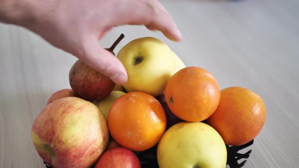 Man Takes an Apple From a Bowl of Fruit