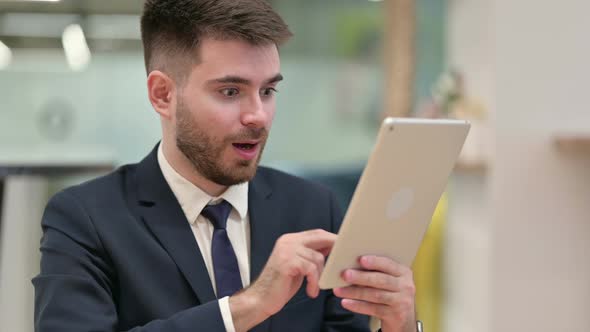 Excited Businessman Celebrating Success on Tablet 