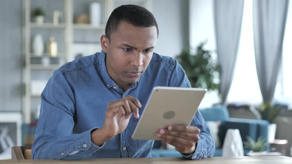 Young African Man Upset for Loss While Using Tablet