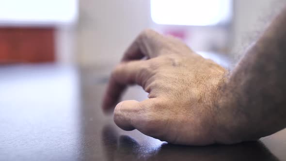 Close up on male hand nervously tapping fingers on table