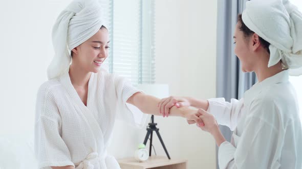 Asian lesbian gay couple put smooth and soft skin care, apply cream lotion after shower with gentle.