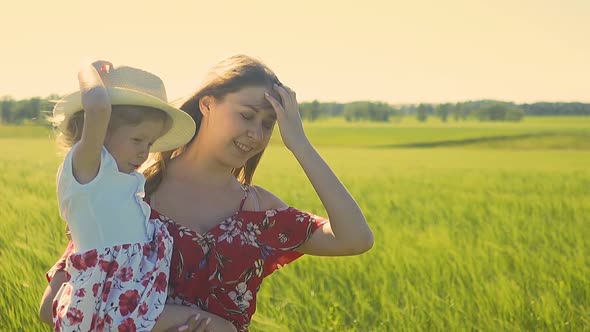 CU, Slow Motion: Mom with Little Daughter in Her Arms, Walking Along Field, They Are Dressed