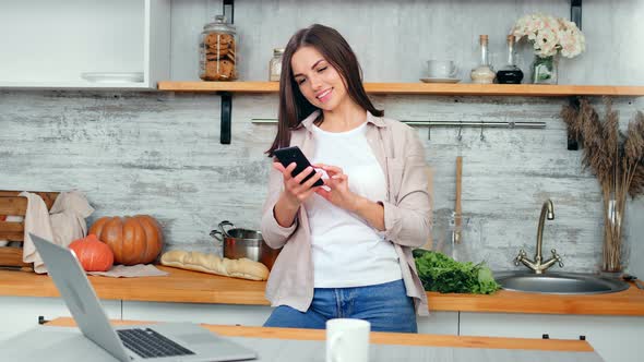 Smiling Beautiful Young Housewife Chatting Using Telephone in Cuisine at Cozy House