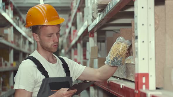 Worker in Helmet Is Checking Materials at the Factory