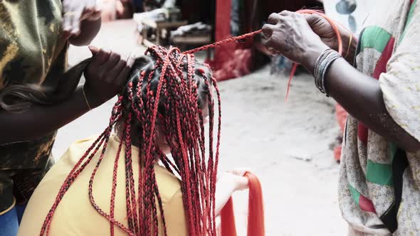 Process of Weaving African Braids with Red Kanekalon Outdoor Zanzibar Africa