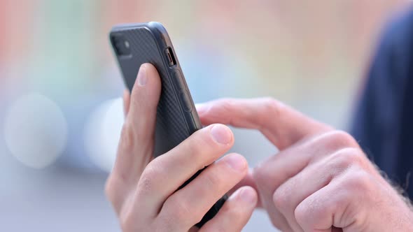 Outdoor Close Up of Hands of Middle Aged Man Scrolling on Smartphone