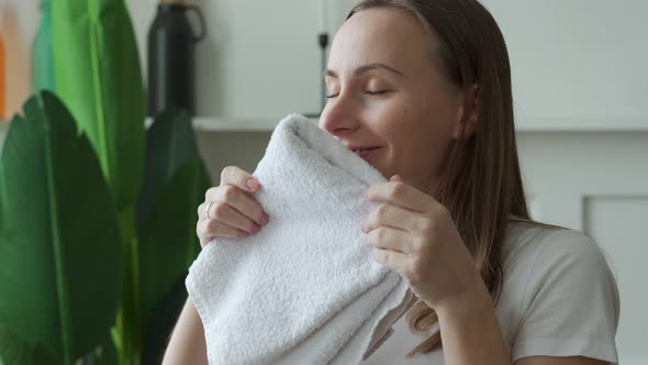 Woman Enjoys Clean and Smelling Towels After Washing at Home