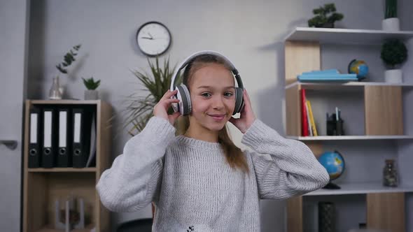 Smiling Teen Girl Looking at Camera while Enjoying Music in Earphones