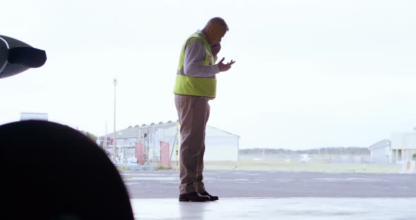 Male engineer talking on mobile phone in hangar 