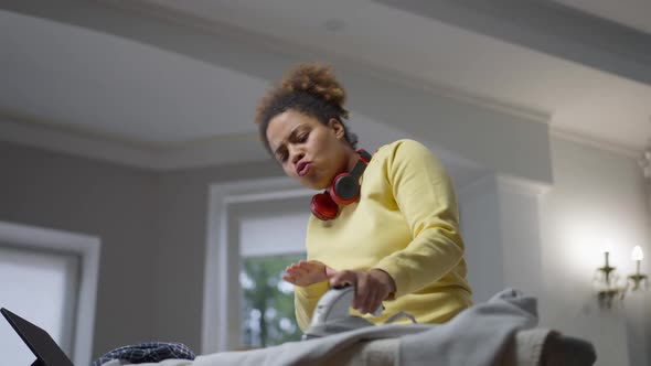 Bottom Angle View of Relaxed Happy African American Housewife Dancing to Music Ironing Laundry at