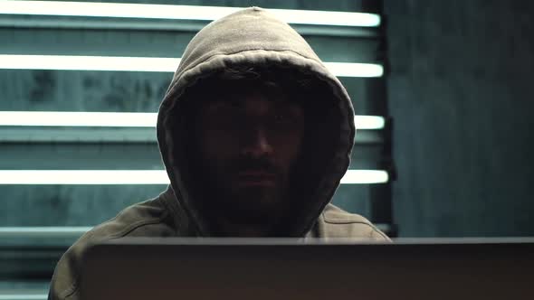 Portrait of Focused Hooded Computer Hacker Breaking Into Government Data Servers, Close-up Face.