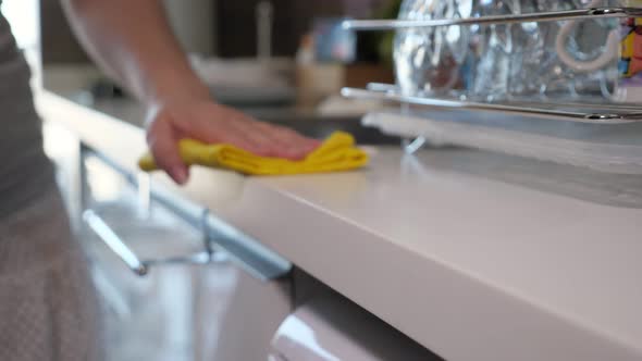 Woman Wipes Kitchen Table Using Yellow Rag, Hand Closeup.