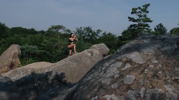Pretty Woman Balancing on One Leg Climbs Cliff