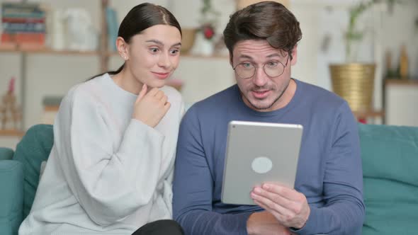 Hispanic Couple Doing Video Call on Tablet While Sitting on Sofa