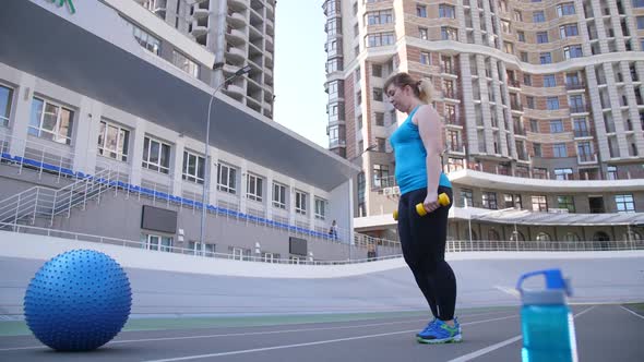 Fat Woman Doing Lunges with Dumbbells in Stadium