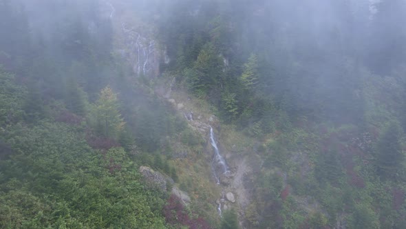 Waterfall in High Mountains in Fog Cloud in Rainy Weather