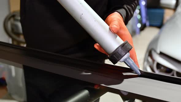 Glazier Applying Rubber Sealing To Windshield in Garage Close Up