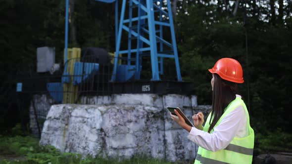 Female Engineer Holds Tablet in Hands and Makes Calculations for Oil Production