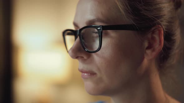 Woman in Glasses Looking on the Monitor and Surfing Internet. The Monitor Screen Is Reflected