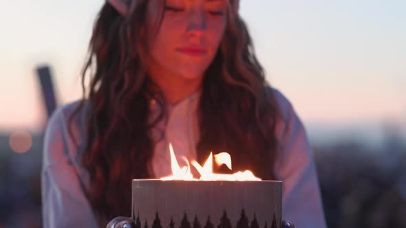 Young woman smiling as she holds small fire fit