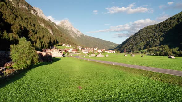 Aerial View of an Austrian Village in a Green Mountain Valley at Sunset Alps