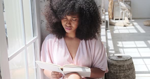 A Young Mixedrace Lady is Attentively Reading an Intriguing Book a Fiction a Novel While Pondering