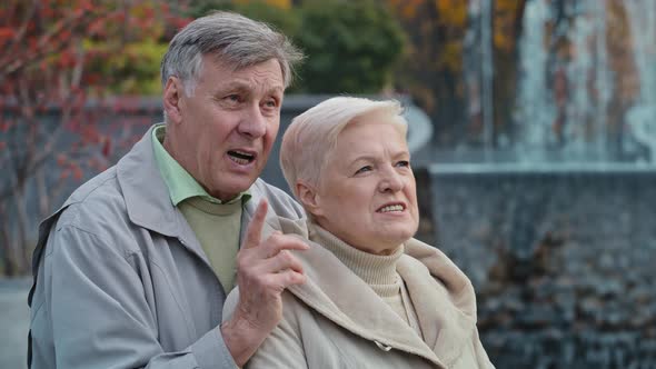 Happy Elderly Married Couple Retired Grandparents Walk in Autumn Park Enjoy Conversation Talk