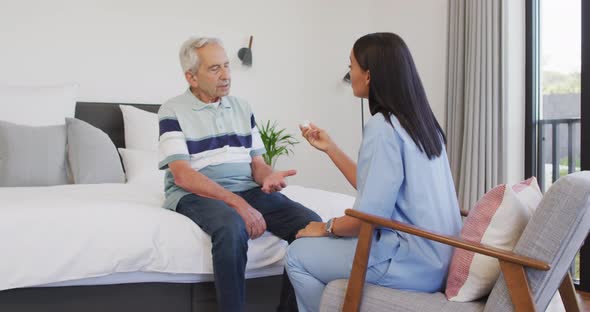 Animation of biracial female doctor giving pills to caucasian senior man