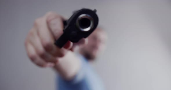 The man threatens with a pistol, points the pistol at the camera. Close-up barrel of a pistol.