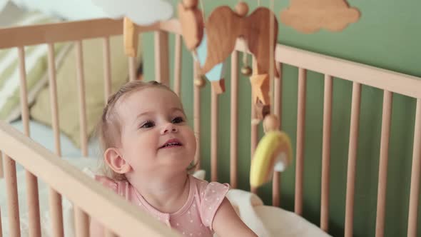 Happy Child Stands in a Crib