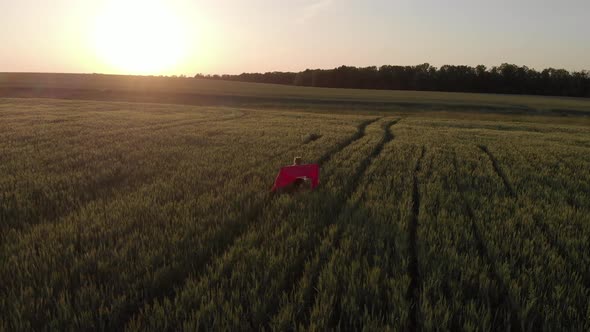 Young Girl Running with Red Tissue in Green Field. Happy Cute Girl Playing in the Wheat Field on a