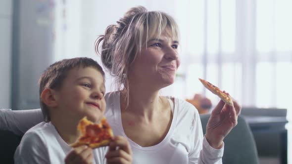 Closeup Mom with Son Eating Pizza and Watching TV