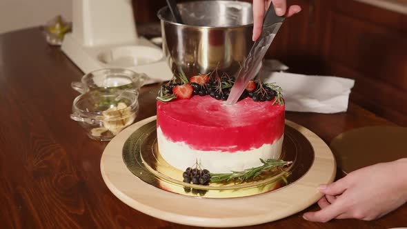 Cook Is Cutting Red Berries Cake , Standing on a Workplace in Kitchen