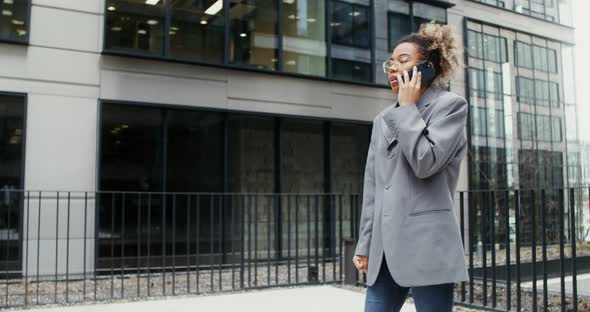 A Woman Using Mobile Phone While Standing Near an Office Building