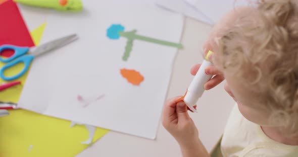 Close Up of Small Girl's Hands Who Puts the Glue on the Cutted From Paper Objects During Making