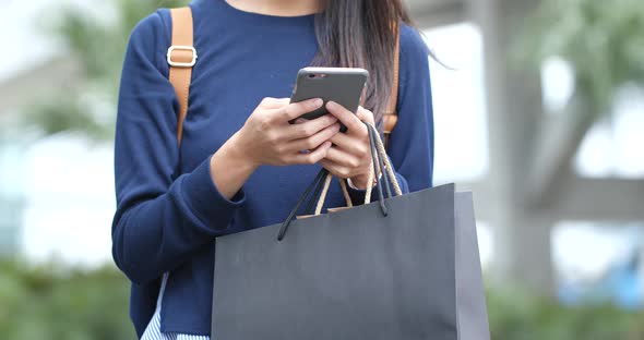 Woman use of mobile phone and hold with shopping bag
