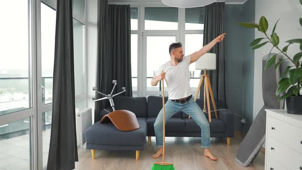 Man Cleaning the House and Having Fun Dancing and Singing with a Broom