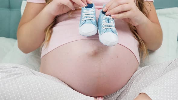 CLoseup of Pregnant Woman Waiting for Baby Boy Holding Small Baby Boots in Hands