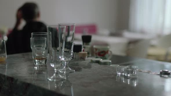 A man is sitting in his kitchen and smoking while drinking wine.