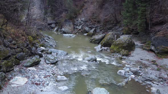 Aerial flying backwards and rising over mountain river, fall