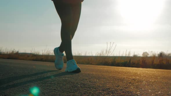 Close Up of Women's Legs Running on Asphalt Road