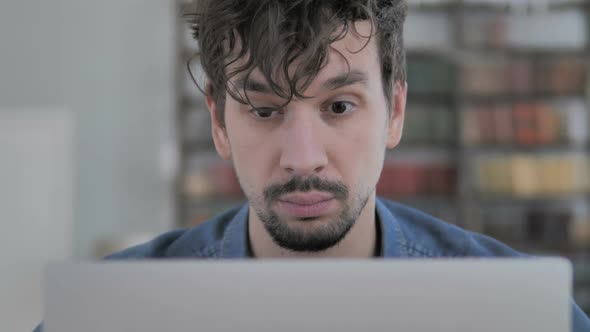 Close Up of Upset Young Man Working on Laptop in Office