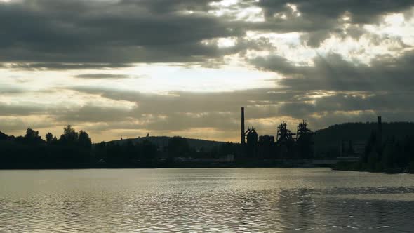 The sun's rays breaking through the grey clouds and illuminate the city pond.