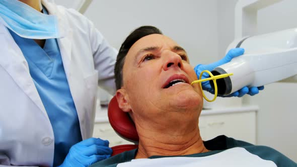 Dentist examining a male patient with tool