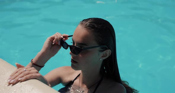 Beautiful Woman Wearing Sunglasses and Swim in the Pool